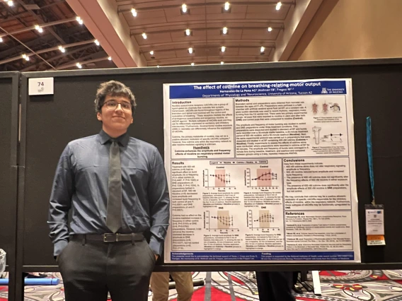 Alessandro Hernandez-De La Pena in front of a presentation poster.